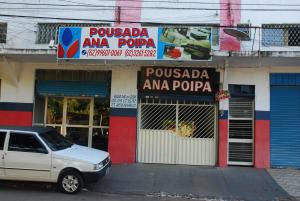 戈亚尼亚Pousada Ana Poipa的把车停在商店前面,把狗放在窗户里