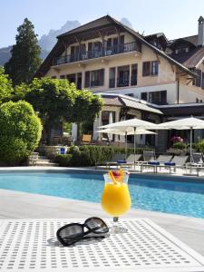 塔卢瓦尔Hotel Le Cottage Bise的坐在游泳池旁的桌子上喝一杯,放上太阳镜