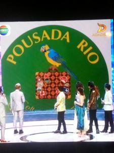 奥斯塔B&B Pousada Rio Aosta-servizi di Bed and breakfast的一群人站在舞台上,在标志上用鹦鹉