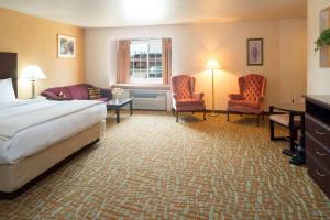 艾尔韦高地艾尔威海兹/斯波坎机场戴斯旅馆及套房酒店的酒店客房,配有一张床和两把椅子
