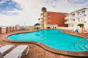 奥蒙德海滩Arya Blu Inn and Suites的一个带椅子和公寓的度假村的游泳池