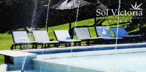 维多利亚Sol Victoria Hotel SPA & Casino的雨中带椅子和遮阳伞的游泳池