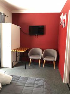 洛坎普顿旅舍汽车旅馆的一间设有两把椅子、一张桌子和一台电视的房间