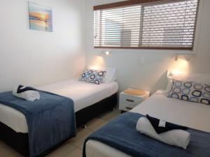 玛志洛Cranbourne Court Beachside Apartments的一间卧室配有两张蓝色和白色的床