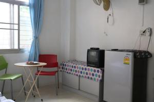 合艾J Home apartment Hadyai的一间小房间,配有冰箱和桌子
