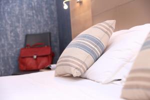 阿尔盖罗阿尔玛迪阿尔盖罗酒店的一张带枕头和红色手提箱的床
