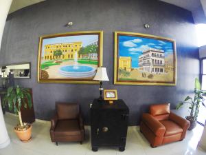 韦拉克鲁斯Hotel Oriente的一间设有两把椅子和墙上绘画的等候室