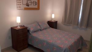 瓜拉派瑞Relax.guarapari的一间卧室配有一张床,并在床头柜上配有两盏灯