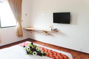 瓜拉丁加奴安特朗西酒店的一间配有电视的房间和一张鲜花盛开的床