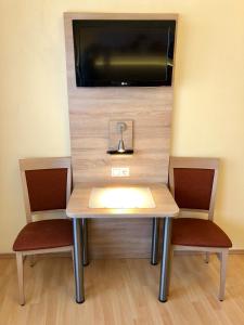 萨尔茨堡萨尔兹堡酒店的一张桌子、两把椅子和墙上的电视