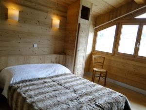 莱热阿尔卑斯花卉小屋酒店的小木屋内的卧室,配有一张床和椅子