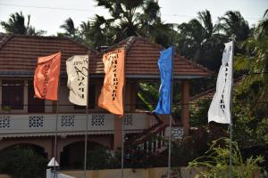 马纳尔Hotel Agape的棕榈树建筑前的三旗