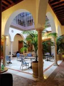 塞维利亚Santiago 15 Casa Palacio的庭院设有桌椅,棕榈树