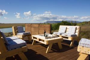 塞尔福斯GreenKey Paradise Cabin的木制甲板配有两把椅子和一张桌子及一瓶