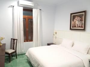 日惹格里亚阿西旅馆的白色卧室配有床和椅子
