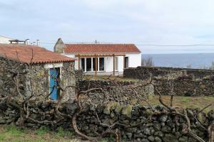 英雄港Canário do Mar - Rural Tourism的一座房子,位于石头墙后面,背靠大海