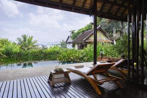 琅勃拉邦La Résidence Phou Vao, A Belmond Hotel, Luang Prabang的一个带桌椅的甲板和一个游泳池