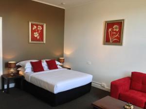 朗塞斯顿Centennial Inn on Bathurst的酒店客房,配有一张床和一张红色椅子