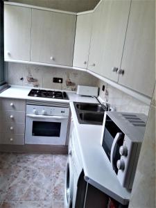 乌贝达Apartamentos Sol Compañia的厨房配有白色橱柜和炉灶烤箱。