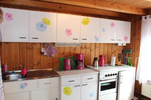 皮得斯费尔德Ferienwohnung Maria的厨房配有白色橱柜和墙上的粉红色鲜花