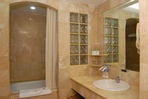 泗水Surabaya Suites Hotel Powered by Archipelago的一间带水槽、浴缸和镜子的浴室