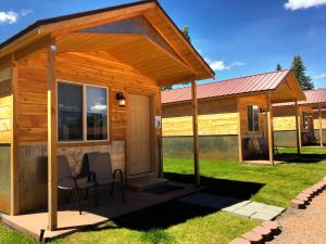 哈奇Mountain Ridge Cabins & Lodging Between Bryce and Zion National Park的小屋设有门廊和草地上的椅子