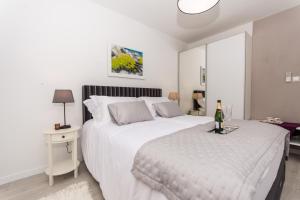 斯普利特Adriatic Blue View的一间白色卧室,配有一张床和一瓶香槟