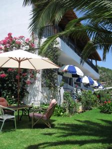 斯基亚索斯镇Skiathos Studios Panorama的庭院配有桌椅和遮阳伞。