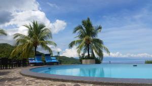 锡基霍尔无限高地度假酒店的海滩上带棕榈树和椅子的游泳池