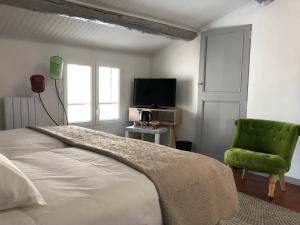 穆斯捷-圣玛丽朱尔旅馆的一间卧室配有一张床和一把绿色椅子