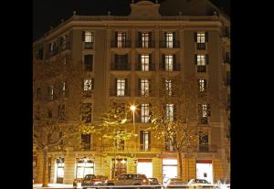 巴塞罗那MH套房公寓式酒店的一座大型建筑,前面有汽车停放