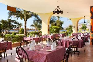 努韦巴TIME Coral Nuweiba Resort的餐厅拥有粉红色的桌椅和棕榈树