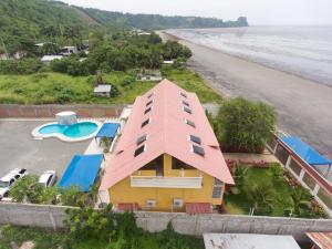 埃斯梅拉达斯Hotel Soberao的海滩旁的黄色房子,有粉红色的屋顶