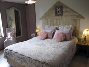 La PommerayeL'Ecurie的卧室配有一张带粉红色枕头的大床