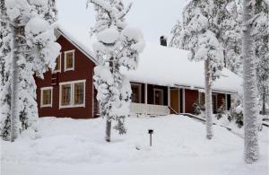 罗瓦涅米Villa Kyyhkynen的前院里被雪覆盖的树木覆盖的房子