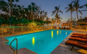 基拉戈大西洋湾度假酒店的游泳池在晚上设有椅子和棕榈树