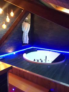 维勒班Le Chalet Loft and Spa的蓝色灯光的客房内的按摩浴缸