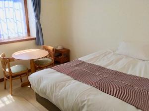 下田奥利奥利住宿加早餐旅馆的一间卧室配有一张床、一张桌子和一个窗户。