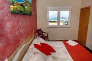 穆希亚Muxia Mare的一间卧室配有一张带红色枕头的床和一扇窗户