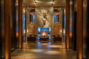 安德马特切蒂安德马特酒店的大堂配有沙发、壁炉和墙上的鹿头