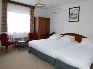穆尔巴赫Hotel-Spa & Restaurant Logis Domaine Langmatt的一间卧室配有一张床、两把椅子和一个窗户