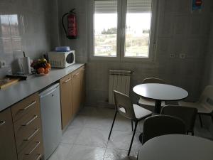 莱昂Hostal Cerecedo的厨房配有桌子、微波炉和桌椅。