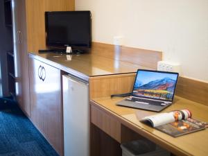 布里斯班Sunnybank Star Hotel的一台笔记本电脑,坐在一张桌子上,配有电视