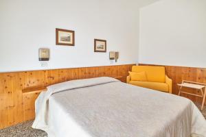 菲纳莱利古雷Albergo Natalina的一间卧室配有一张床和一张黄色椅子