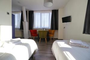 波尔代克圣文森特酒店的酒店客房带两张床和一张桌子以及椅子。