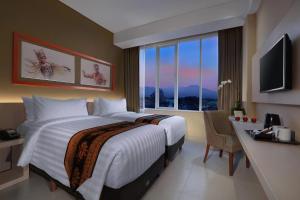 外南梦ASTON Banyuwangi Hotel and Conference Center的酒店客房设有两张床、一张书桌和一个窗户。