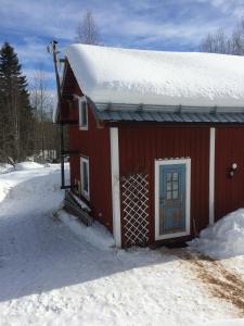 马隆Stuga Petruslogen的雪中带雪盖屋顶的红色房子