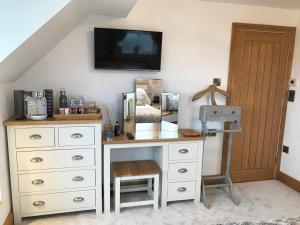 PentraethLon y Traeth Bed & Breakfast的白色梳妆台、书桌和墙上的电视