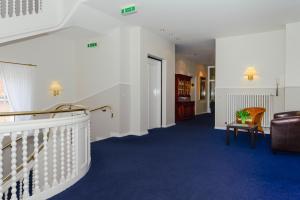 威克奥夫弗尔Kurhaus Hotel的走廊设有楼梯、沙发和椅子