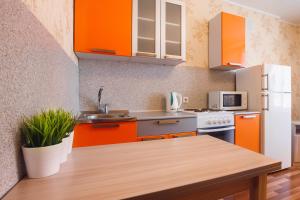 托木斯克Апартаменты на Савиных的厨房配有橙色橱柜和木桌